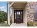 Inviting front entrance featuring a dark wood door with glass panels, surrounded by stone and brick accents at 164 Arabella Ct, Cary, NC 27518