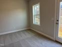 A well-lit bedroom with neutral carpet, a bright window, and a glass door to the outside at 1913 Fishamble St, Fuquay Varina, NC 27526