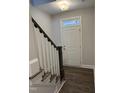 Inviting entryway with hardwood floors, a white front door and staircase with dark wood railing at 1913 Fishamble St, Fuquay Varina, NC 27526