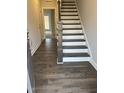 Inviting foyer with dark wood-look floors and staircase featuring stained banister and white risers at 1913 Fishamble St, Fuquay Varina, NC 27526