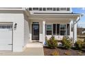 Charming front porch with a seating area, black door, and neatly trimmed landscaping at 277 Martins Mill Ct, Wendell, NC 27591