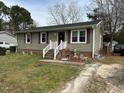 A single-story home with vinyl siding and a front yard with mature trees and small staircase to enter at 402 Todd Hill Dr, Wendell, NC 27591