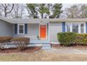 Close up of the front of a home with a striking orange door, gray siding and blue shutters at 4814 Fayetteville Rd, Durham, NC 27713