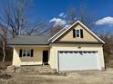 Charming home featuring a bright yellow exterior, stone accents, and an attached garage under a cloudy blue sky at 512 Hicksmill Rd, Oxford, NC 27565