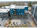 Aerial view of a modern blue building with balconies and parking, surrounded by lush greenery and urban landscape at 515 N Mangum St # 14, Durham, NC 27701