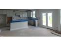 Bright, unfinished kitchen with white cabinets, a center island, and a double glass door to the exterior at 72 Cultivator Ct, Angier, NC 27501