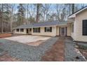 A ranch style house with a concrete driveway and light yellow vinyl siding, with brick pavers and gray pea gravel at 7214 Southern Trl, Chapel Hill, NC 27516