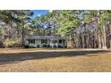 Inviting single-story home featuring a well-kept lawn and surrounded by lush, mature trees at 749 Fred Royster Rd, Henderson, NC 27537