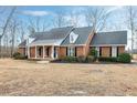Brick home with a gabled roof and black shutters is surrounded by trees and a grassy yard at 8724 Ten Ten Rd, Raleigh, NC 27603