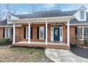 Covered porch of brick home has white columns and black shutters on its many windows at 8724 Ten Ten Rd, Raleigh, NC 27603