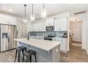 Bright kitchen with white cabinets, stainless appliances, an island with stools, and hardwood floors at 94 Paperwhite Pl, Clayton, NC 27527