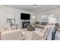 Comfortable living room featuring neutral-toned sofas, a fireplace, and a large window with natural light at 94 Paperwhite Pl, Clayton, NC 27527