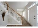 Bright foyer with hardwood floors, white staircase and view into another room at 122 Banyon Tree Ln, Cary, NC 27513