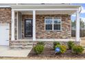 Inviting front porch with stone accents and an ADT security sign in the manicured garden at 140 Baker Farm Dr, Youngsville, NC 27596