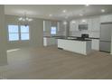 Open concept kitchen with white cabinets, large island, stainless appliances, and wood floors at 148 Mohawk Dr, Louisburg, NC 27549