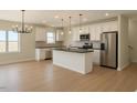 Bright, modern kitchen with stainless steel appliances, central island, pendant lighting, and sleek white cabinets at 148 Mohawk Dr, Louisburg, NC 27549