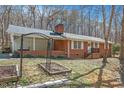 Charming brick home featuring a covered porch, garden area, and cozy outdoor space at 1614 Clearwater Lake Rd, Chapel Hill, NC 27517