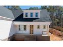 The white-painted front porch is accented by brick stairs and is set in a serene wooded neighborhood at 215 Purslane Dr, Franklinton, NC 27525