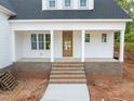 Inviting front porch with brick steps, columns, and a wood front door at 215 Purslane Dr, Franklinton, NC 27525