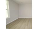 Bright living room featuring light gray walls, hardwood floors, and a large window showcasing the outdoor scenery at 2454 Englemann Dr # 380, New Hill, NC 27562