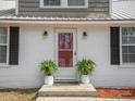 Welcoming front entrance with a storm door, brick facade, potted ferns, and updated lighting fixtures at 3130 State Hwy 58, Louisburg, NC 27549