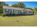Cozy single-story home with a well-kept lawn, enhanced by neatly trimmed shrubs and a vibrant American flag at 7850 Nc 42, Holly Springs, NC 27540