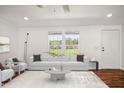 Bright living room featuring modern white furniture, hardwood floors, and plenty of natural light at 7850 Nc 42, Holly Springs, NC 27540