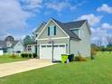 Side view of home with a basketball hoop, two-car garage, and well-kept lawn at 897 W Main St, Benson, NC 27504