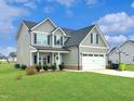Beautiful two-story home with a well-maintained lawn, a covered porch and attached garage at 897 W Main St, Benson, NC 27504