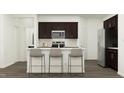 Modern kitchen featuring an island with seating, dark cabinetry, and stainless-steel appliances at 10068 Regal Dr, Angier, NC 27501