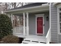 Inviting front porch area with white columns and a red front door at 113 Hawkscrest Ct, Apex, NC 27502