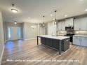 Open kitchen with large island, stainless appliances, and modern lighting fixtures at 1794 Parham Dr, Graham, NC 27253