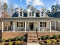 Inviting front porch with brick base, black railings, and ample seating space, perfect for relaxing outdoors at 290 Whistlers Cv, Louisburg, NC 27549