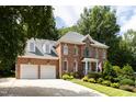 Stately brick home with a two-car garage, manicured lawn, and mature trees creates a picturesque and inviting curb appeal at 3359 Hampton Rd, Raleigh, NC 27607