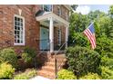 Close-up of the brick home's front porch with blue door, showcasing the American flag and manicured landscaping at 3359 Hampton Rd, Raleigh, NC 27607