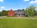 Beautiful two-story brick home with black shutters, white columns, and a well-manicured lawn at 93 Shoreline Dr, Princeton, NC 27569