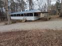 Single-story home features a long screened porch and covered parking, with a gravel driveway and woodsy surroundings at 122 Tomahawk Dr, Louisburg, NC 27549