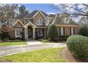 Beautiful two-story home with a stone and brick exterior, a manicured lawn, and a charming front porch with double-door entrance at 12417 Richmond Run Dr, Raleigh, NC 27614