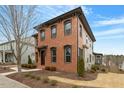 Corner view of a beautiful brick house featuring black trim and landscaping, with a glimpse of the side entrance at 1354 Briar Chapel Pkwy, Chapel Hill, NC 27516