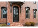 Close-up of an arched front door, brick facade, and manicured landscaping, highlighting the home's architectural details at 1354 Briar Chapel Pkwy, Chapel Hill, NC 27516