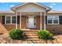 Close up of brick home featuring a classic design and inviting front porch at 2103 Huntington Rd, Burlington, NC 27215