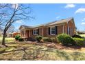 Well-maintained brick home with black shutters, landscaped yard, and a cozy side porch at 2103 Huntington Rd, Burlington, NC 27215