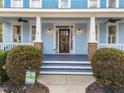 Inviting front porch with a decorated wooden door, porch lighting, and manicured landscaping at 2118 Cloud Cover Ln, Raleigh, NC 27614