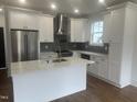 Modern kitchen with stainless appliances, white cabinetry, an island with a sink, and stylish backsplash at 2214 Woodrow St, Durham, NC 27705