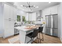 Modern kitchen featuring white cabinets, stainless steel appliances, marble countertops, and island with seating at 2218 Woodrow St, Durham, NC 27705