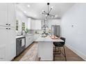 Stylish white kitchen features stainless steel appliances, modern light fixture, island with chairs, and hardwood floors at 2218 Woodrow St, Durham, NC 27705