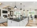 Open-concept kitchen with a black marble island, white cabinets, and a view into the adjacent living room at 2404 Del Webb Gardens Dr, Fuquay Varina, NC 27526