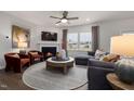 Cozy living room featuring a fireplace, a ceiling fan, and ample natural light from large windows at 424 Providence Springs Ln, Fuquay Varina, NC 27526