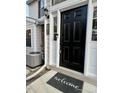 Close-up of the front door with a 'welcome' mat, black door, and white trim at 7708 Falcon Rest Cir, Raleigh, NC 27615