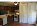 Functional kitchen boasts wood cabinets, white appliances, and closet storage at 7746 Kingsberry Ct, Raleigh, NC 27615